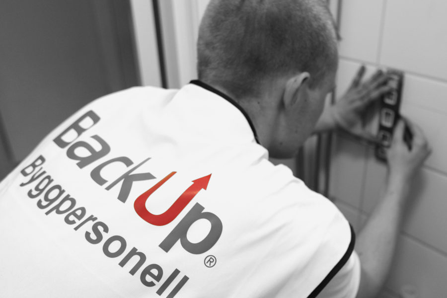 Person i arbeid med flis med backup byggpersonell logo på ryggen